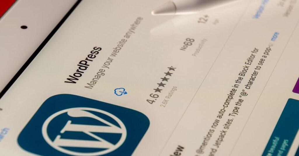 Close-up of a tablet screen displaying the WordPress app page, highlighting its 4.6-star rating from 26K users and the tagline Manage your website anywhere. The stylus hints at effortless control and trusted WordPress stability.